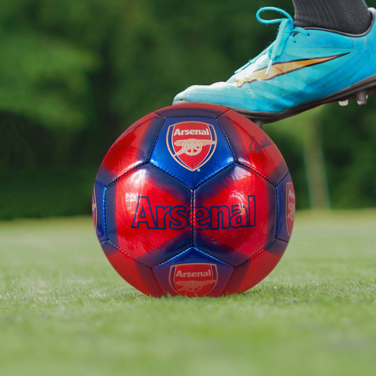 Arsenal Metallic Signature Football in red and blue being kicked on a grass field