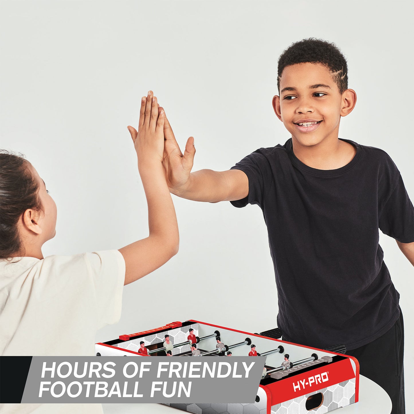 Kids high fiving while playing Hy-Pro 20" Table Top Football Table on a white background.