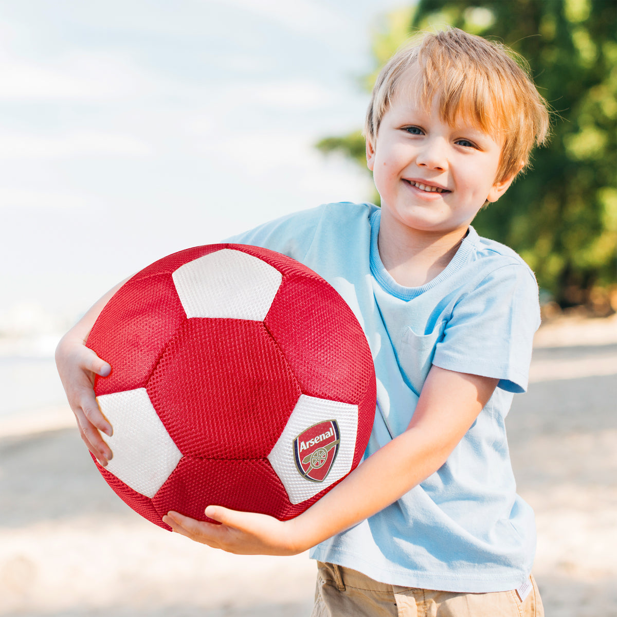 Arsenal Giant 14in Mesh Ball in red and white being held by a young boy on a beach