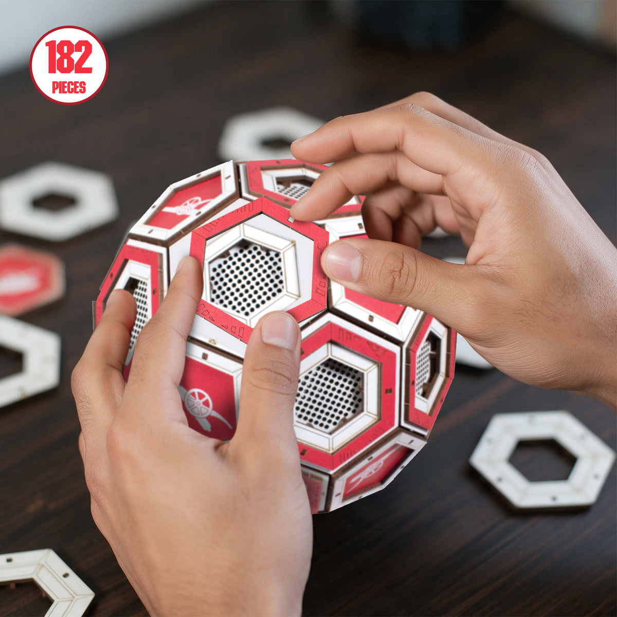 Hands constructing the wooden display football with a sign in the top left reading ' 182 pieces'