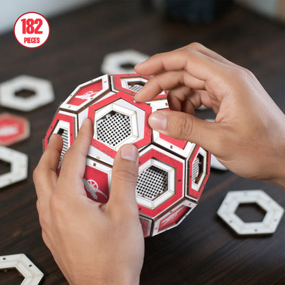 Hands constructing the wooden display football with a sign in the top left reading ' 182 pieces'