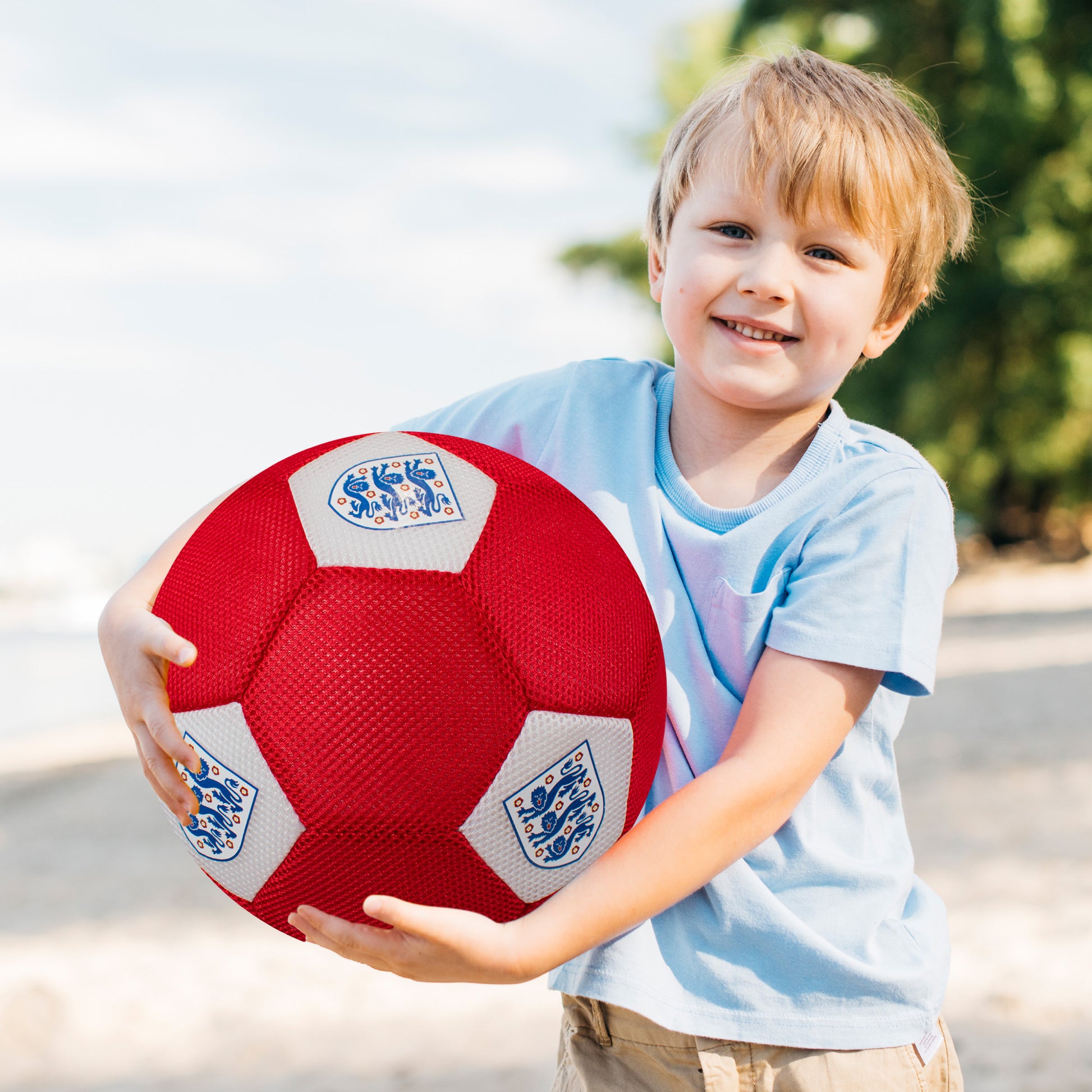 Little boy holding Officially licensed England FA 3 lions giant mesh football in red and white by hy-pro sports on a white background