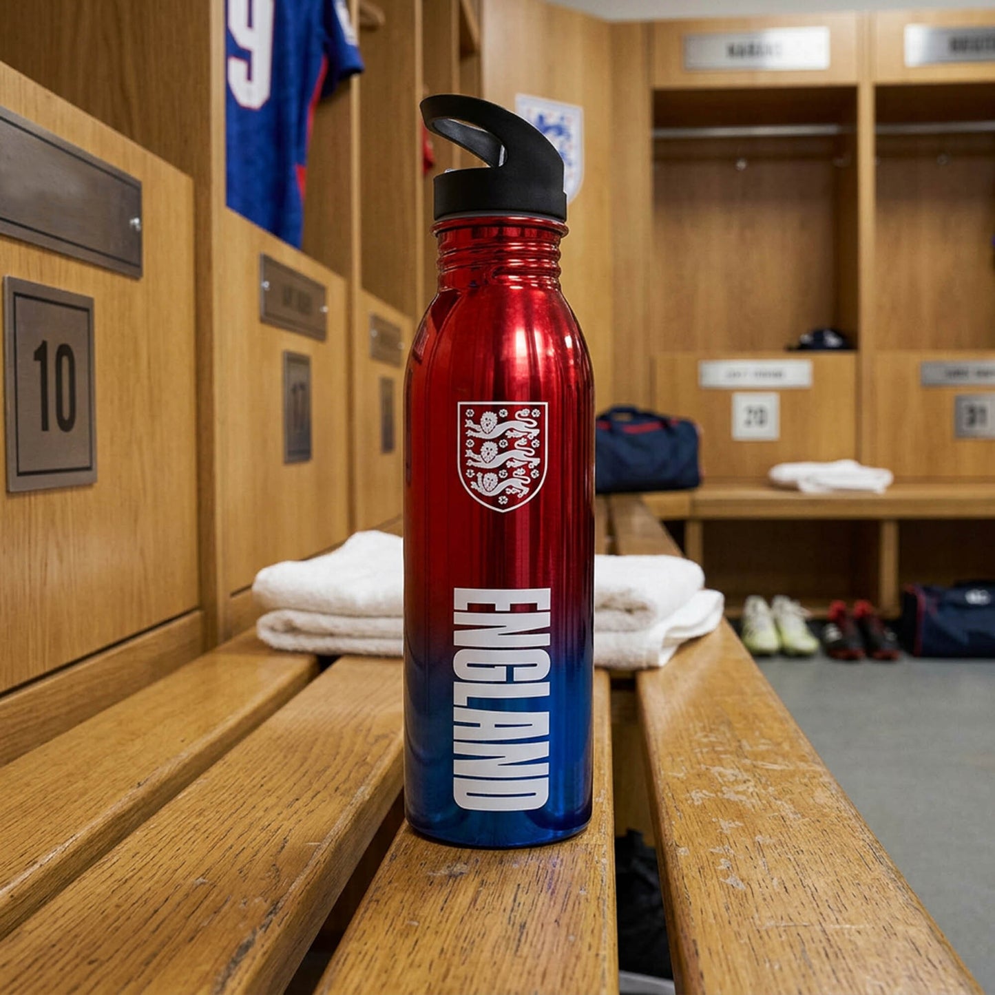 Official England 3 Lions bottle in red and blue with 3 lions badge in a locker room setting 