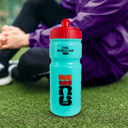 FIFA WORLD CUP 2026 FOOTBALL GIFT SET WATER BOTTLE ON A GRASS FOOTBALL PITCH NEXT TO A PLAYER SAT ON THE FLOOR