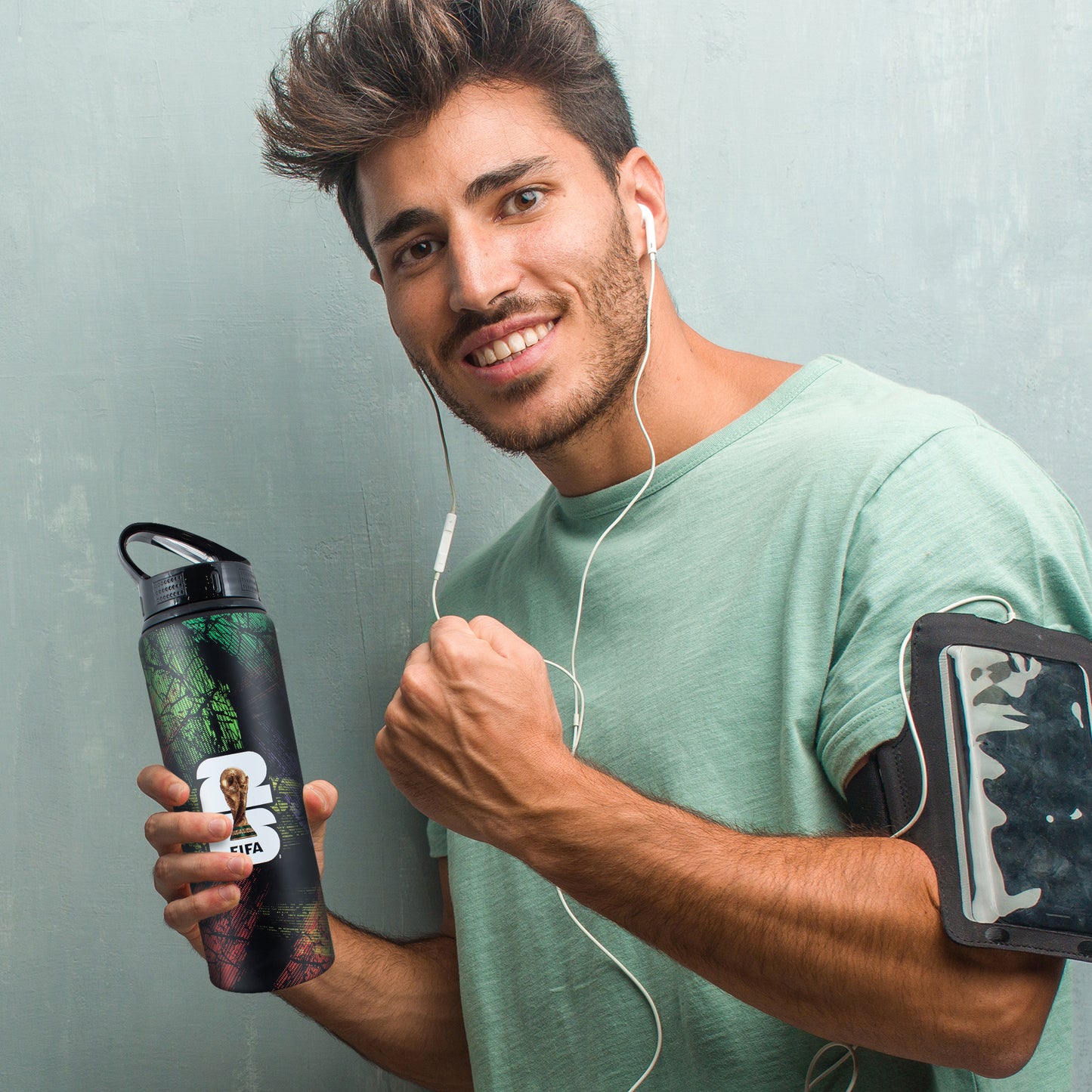 FIFA WORLD CUP 2026 750ML ALUMINIUM WATER BOTTLE BY HY-PRO SPORTS BEING HELD BY A PERSON ON A GREY BACKGROUND
