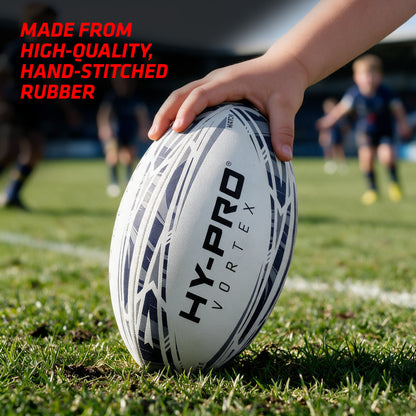 Hy-Pro Vortex Rugby Match Ball on a grass rugby pitch with a hand holding it in place and copy which reads ' ADE FROM HIGH-QUALITY HAND-STICHED RUBBER'