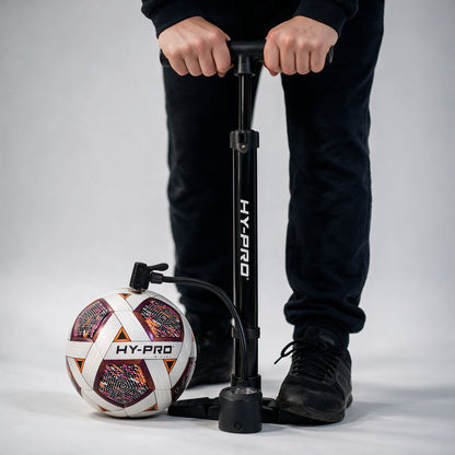 black football pump being used to inflate football with a grey background 