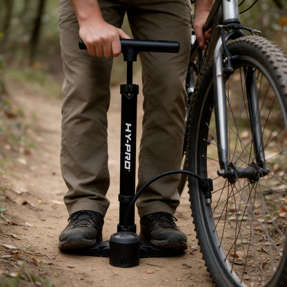 Black stirrup pump inflating a bike wheel in the woods
