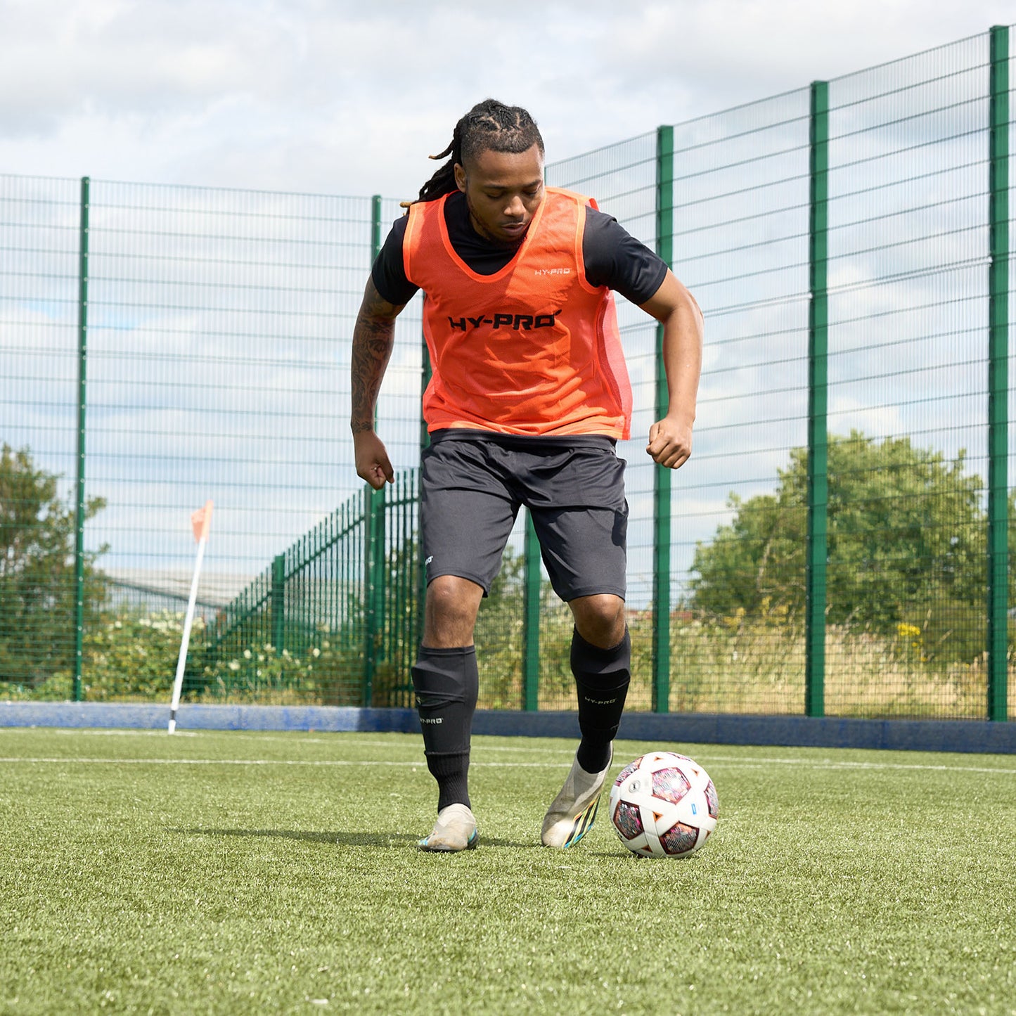 Hy-Pro Official FIFA Quality Approved, Match, Size 5 Football ball being dribbled across a football pitch by a player in an orange HY-PRO sports bib