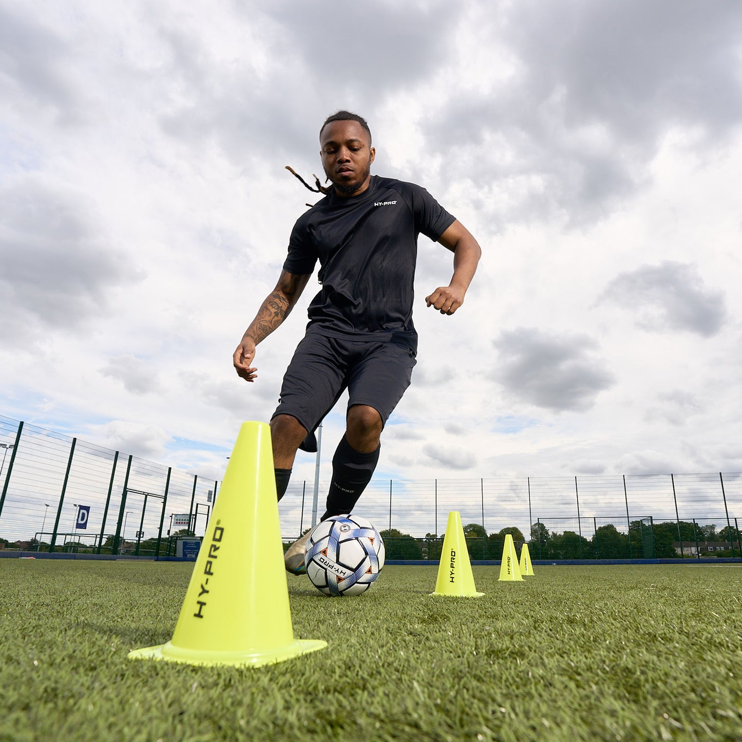 Hy-Pro Sports Malicia Football being dribbled through tall yellow cones on a grass pitch