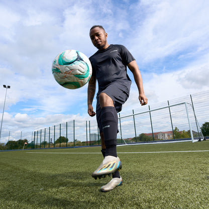 Hy-Pro Sports Shin Pads being worn by a football player kicking a football into the air on an Astroturf pitch