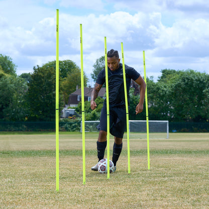Hy-Pro Sports Yellow agility poles on a grass football field with a ball being dribbled through the poles by a football player