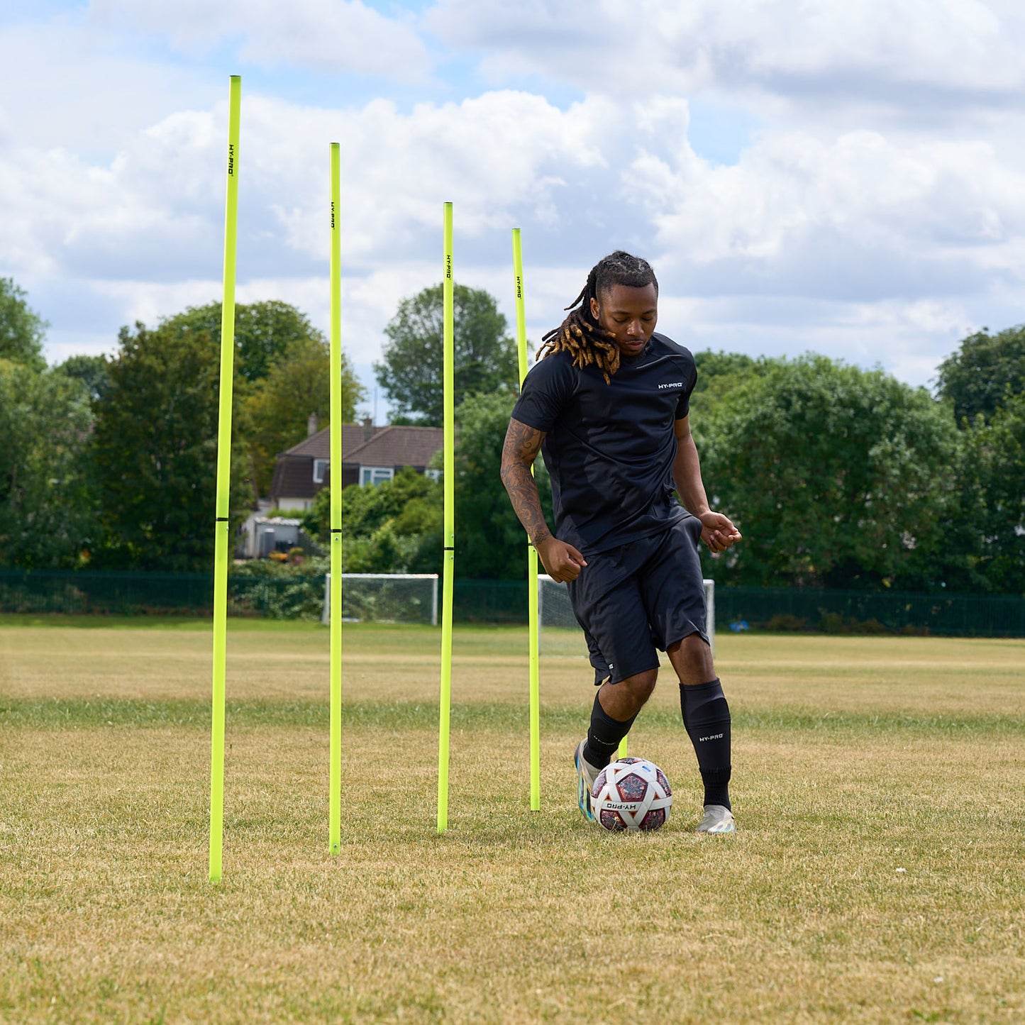 Football player passing a ball through eh Hy-Pro sports agility poles on a football field