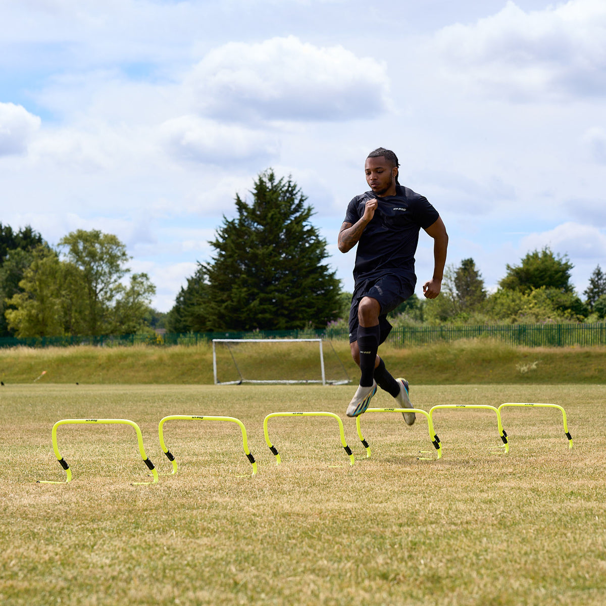 A football player using the Hy-Pro Sports adjustable hurdles on a grass football pitch running through them