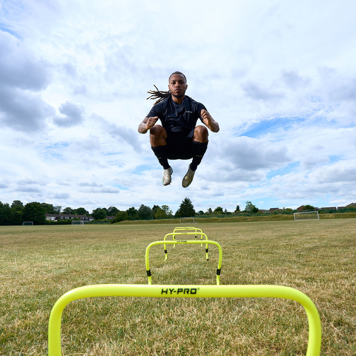 Action shot of a Footballer jumping over the Hy-Pro Sports adjustable hurdles on a grass football pitch