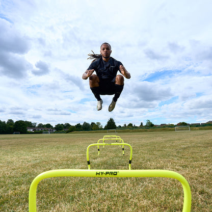 Action shot of a Footballer jumping over the Hy-Pro Sports adjustable hurdles on a grass football pitch