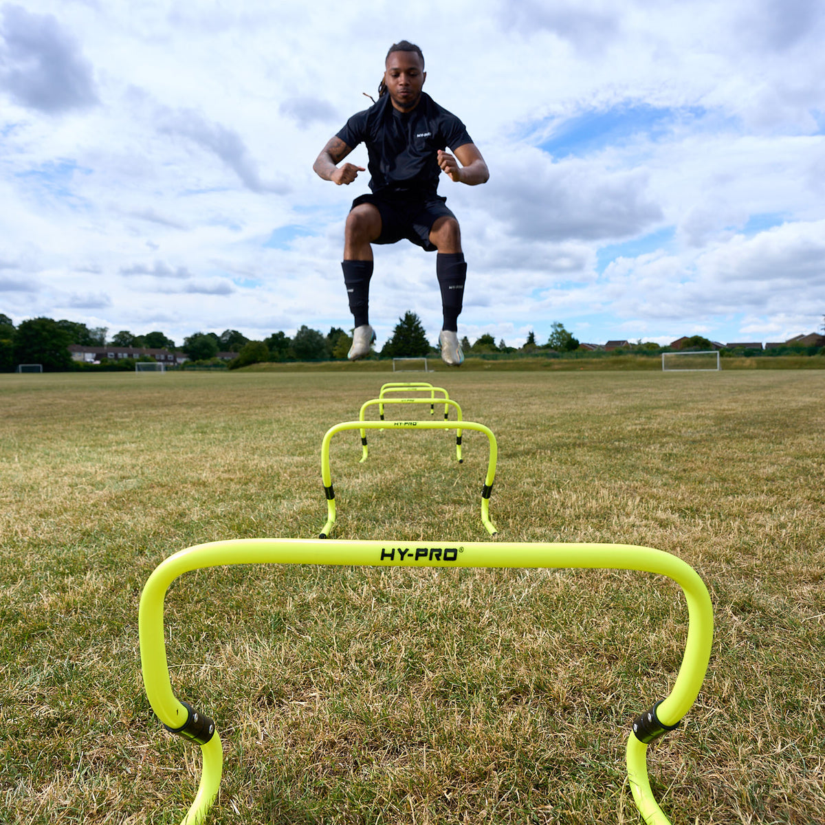 Footballer jumping over the Hy-Pro Sports adjustable hurdles on a grass football pitch