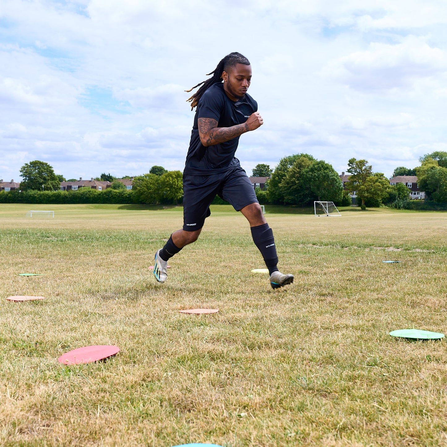 Football player agility training in a field running between flat floor markers