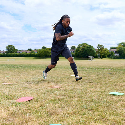 Football player agility training in a field running between flat floor markers