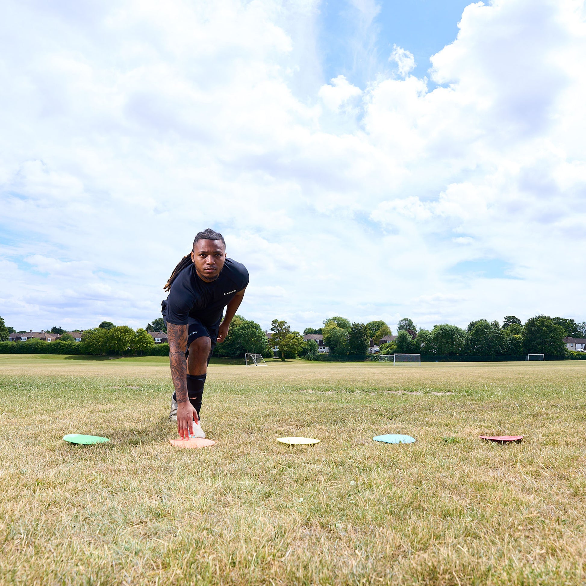 Football player agility training on a grass pitch running between colourful floor markers by Hy-Pro Sports