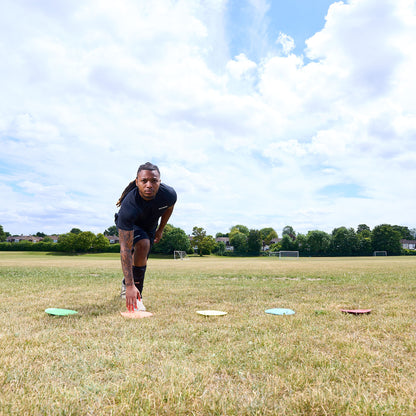 Football player agility training on a grass pitch running between colourful floor markers by Hy-Pro Sports