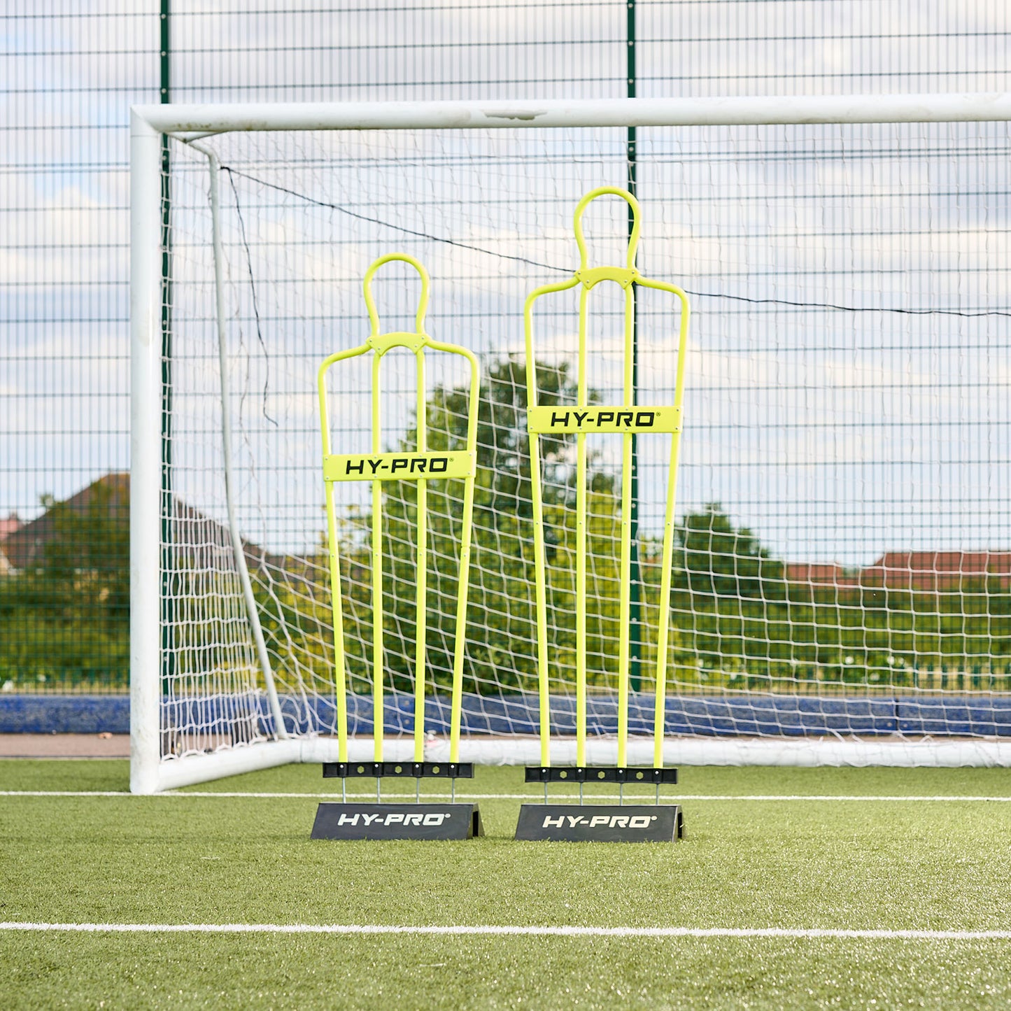 Youth and Adult sized Hy-Pro defender dummy's side by side in front of a football goal on a pitch