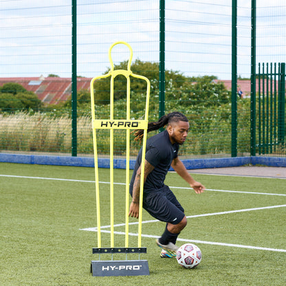 Adult Hy-Pro Defender Dummy with rubber base on an Astroturf pitch with a footballer dribbling a ball around it