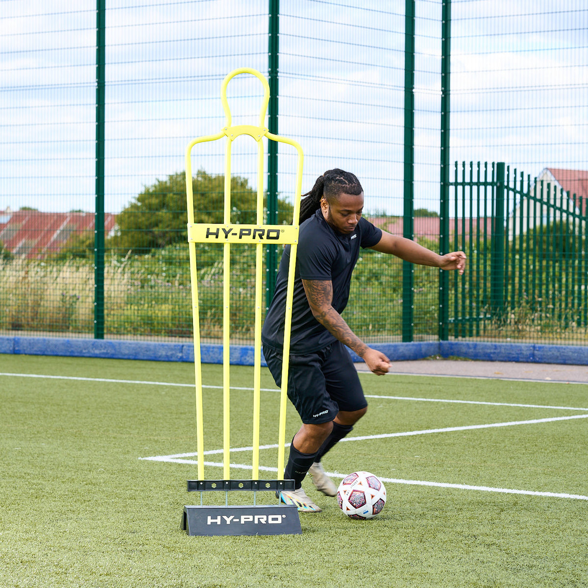 Hy-Pro sports rubber base and defender dummy on an Astroturf pitch while a player trains around it 