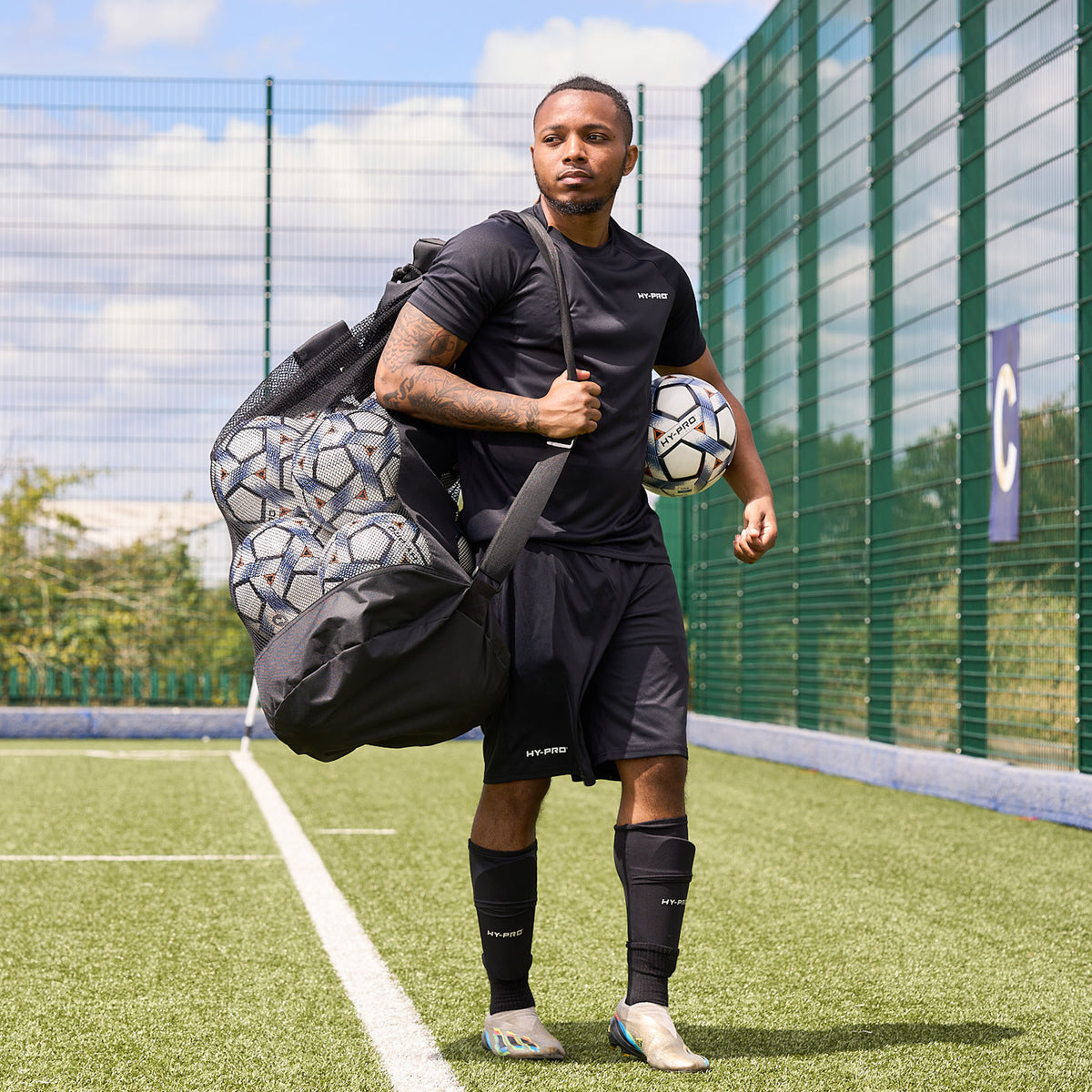 Football player using the HY-PRO Sports Jumbo ball bag to carry footballs across a pitch