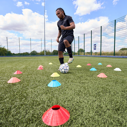 Footballer training dribbling skills on an Astroturf pitch using the scatter cone method with Hy-Pro Sports cones