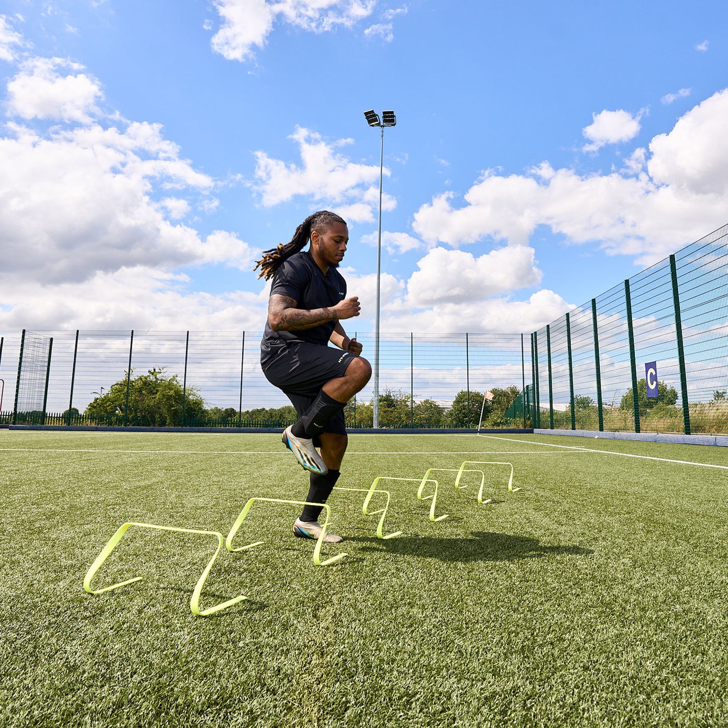Football player training on an Astroturf pitch using the Hy-Pro sports flat agility hurdles