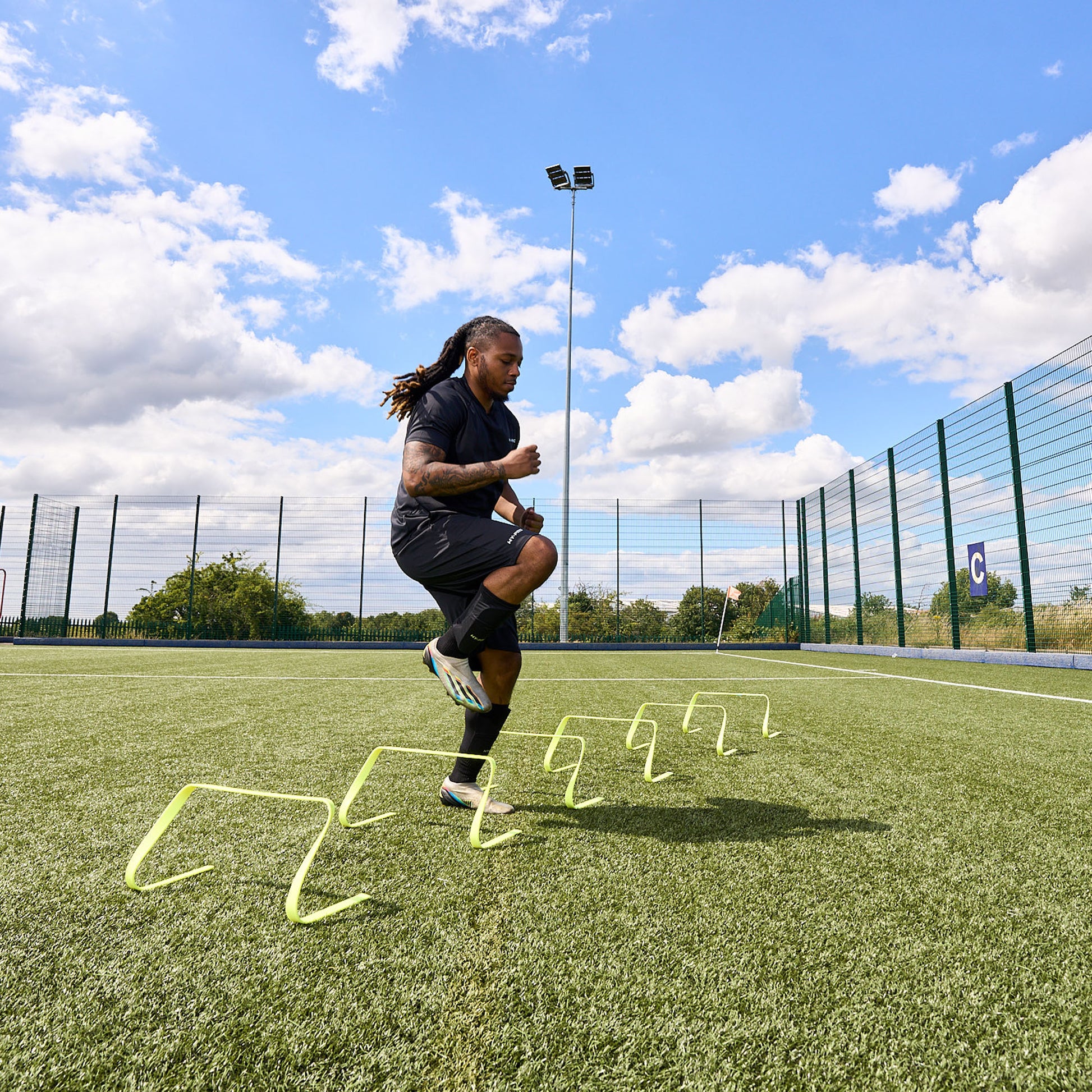 Football player training on an Astroturf pitch using the Hy-Pro sports flat agility hurdles