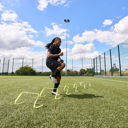 Football player training on an Astroturf pitch using the Hy-Pro sports flat agility hurdles