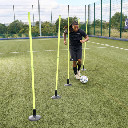 In action photo of a footballer kicking a ball through agility hurdles on an Astroturf pitch