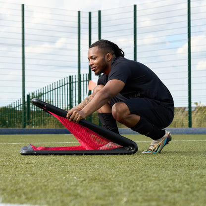 Footballer demonstrating how to erect a hy-pro sports 3v3 goal on an Astroturf pitch