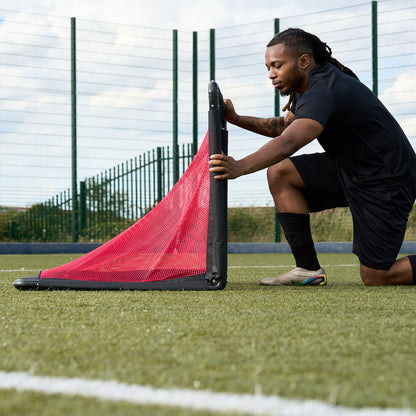 Footballer unfolding the Hy-Pro Sports Alu foldable goal into place on an Astroturf pitch