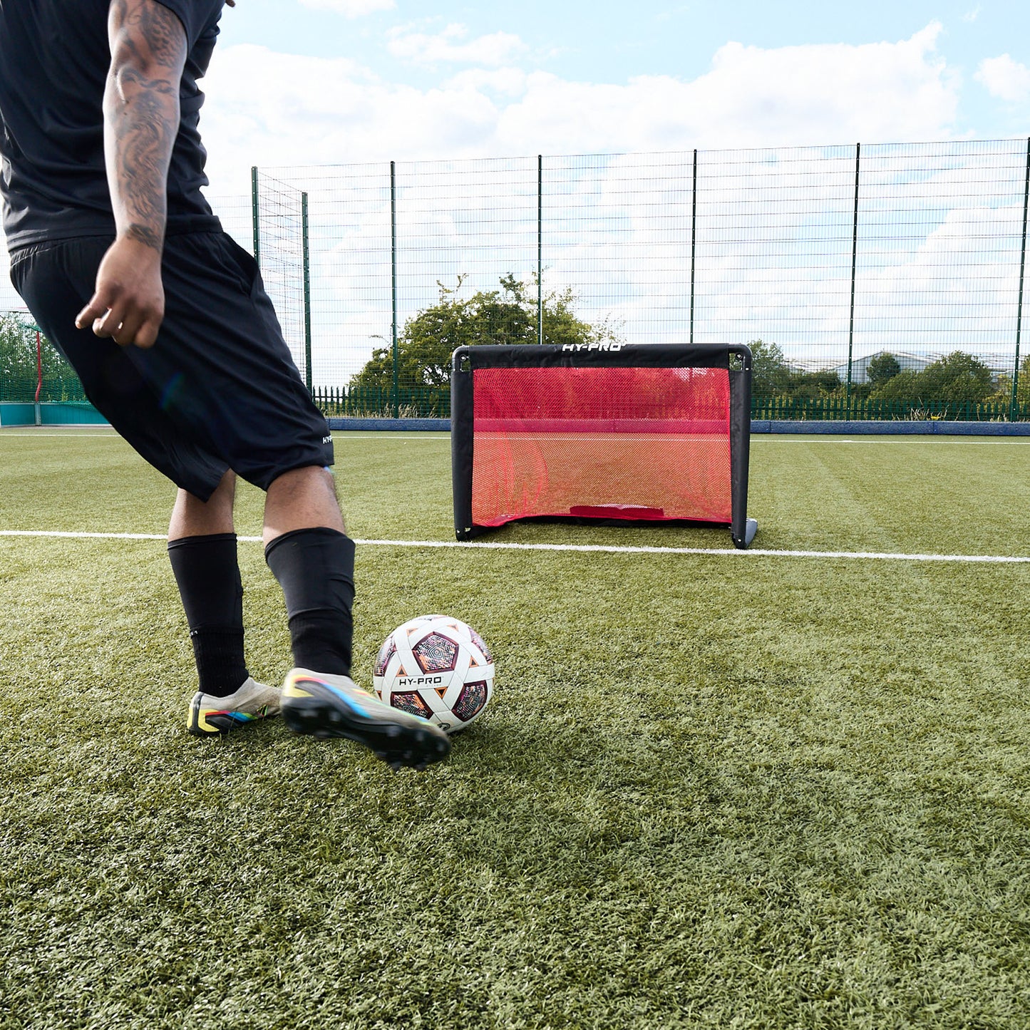 Footballer kicking football towards Hy-Pro Alu foldable goal on a football pitch 