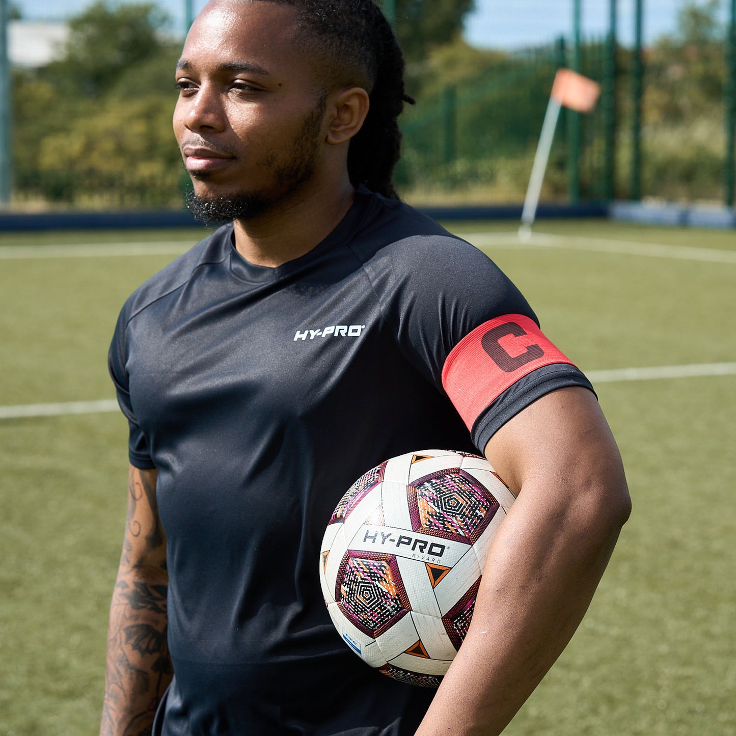 Hy-Pro Captains Arm band in red being worn by a footballer holing a HY-Pro ball on a football pitch