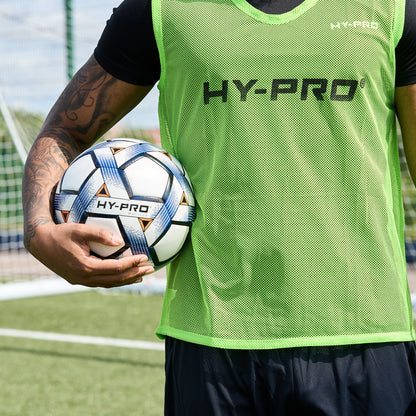 Hy-Pro Sports bib in Green with HY-PRO branding being worn by a football player on a pitch holding a football