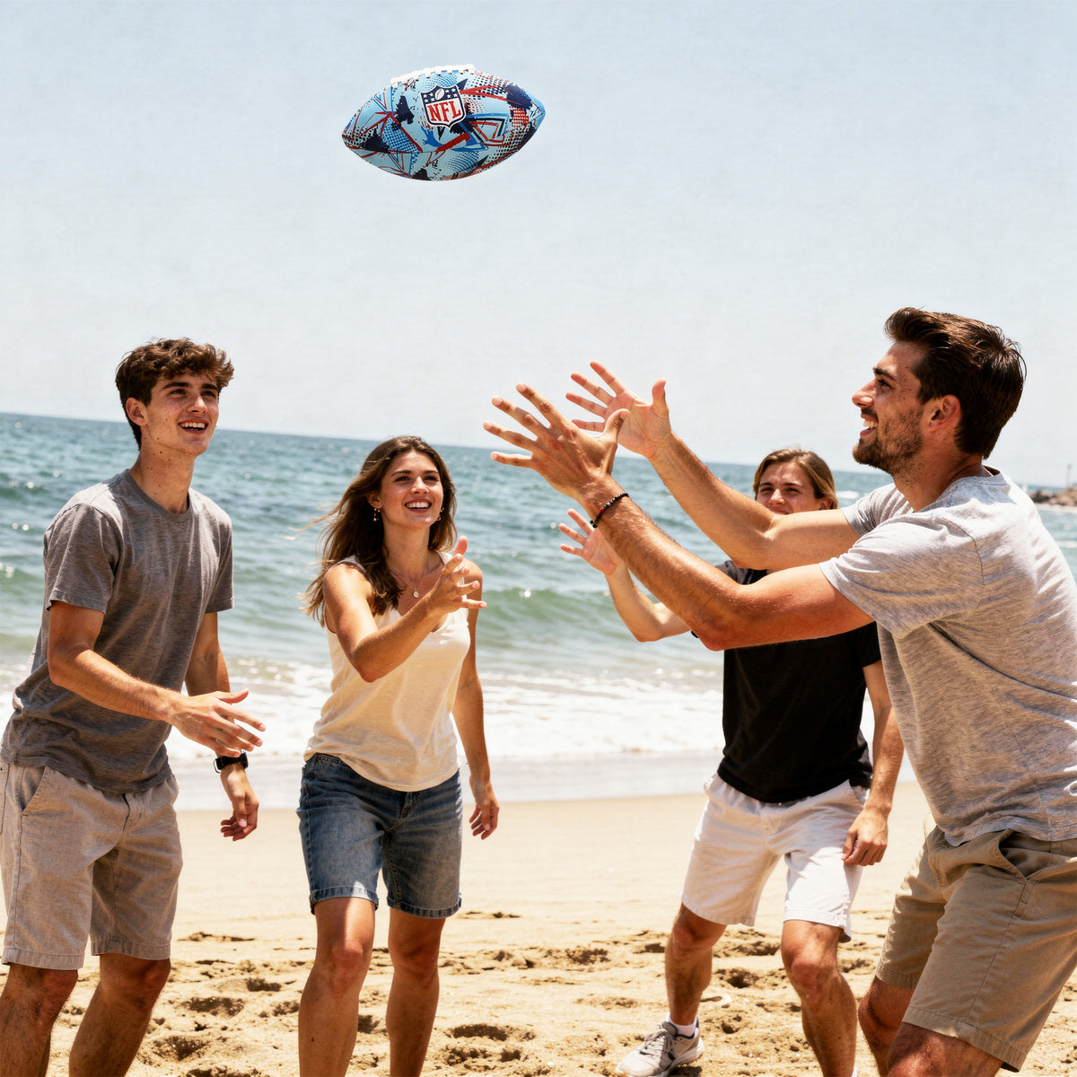 group of people playing catch wiht the NFL Neoprene football in blue and red with NFL logo on a sandy beach