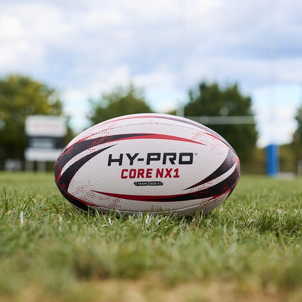 HY-PRO Match Rugby ball in white, black and red sat on a rugby pitch
