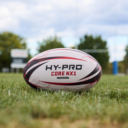 HY-PRO Match Rugby ball in white, black and red sat on a rugby pitch